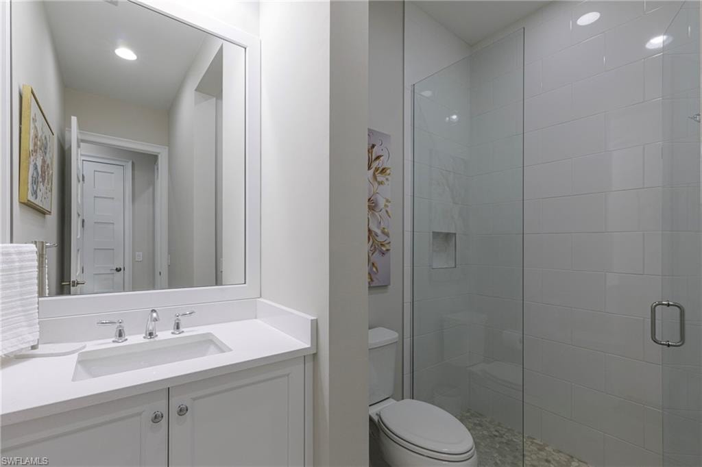 Bathroom with a stall shower, vanity, and recessed lighting