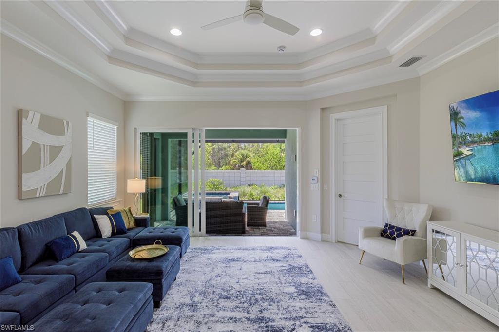 Living room with plenty of natural light, crown molding, recessed lighting, a raised ceiling, and light wood-type flooring