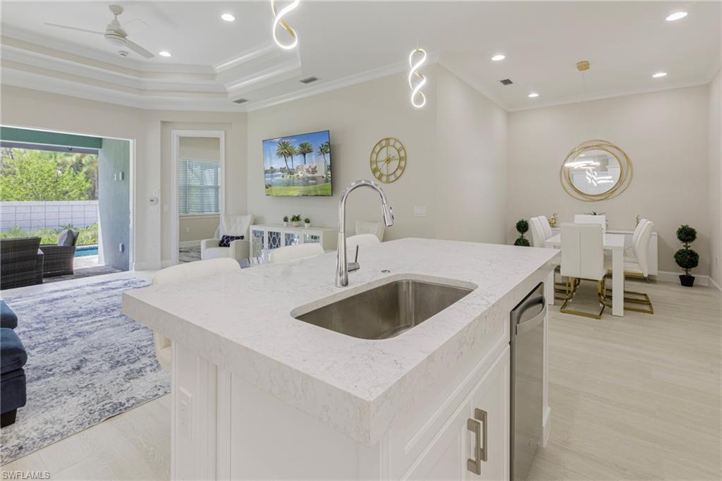 Kitchen with open floor plan, recessed lighting, ornamental molding, hanging light fixtures, and light stone counters