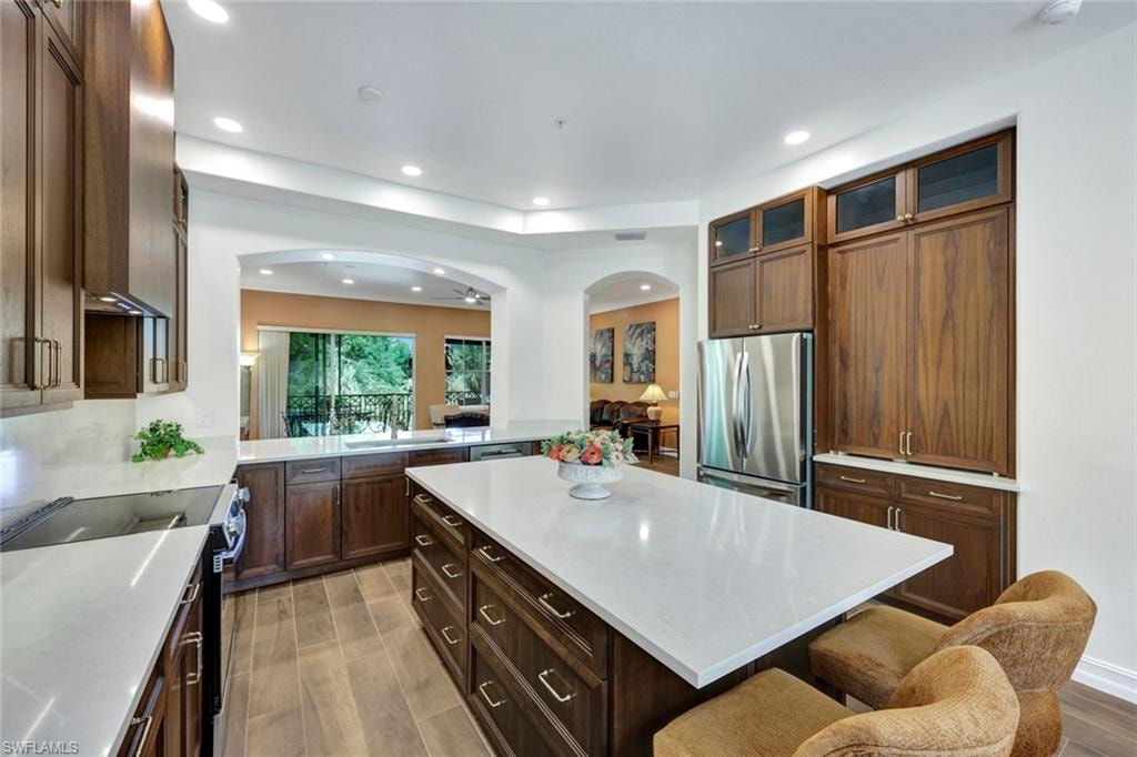 Kitchen featuring electric range, a kitchen bar, light wood-type flooring, a kitchen island, and freestanding refrigerator