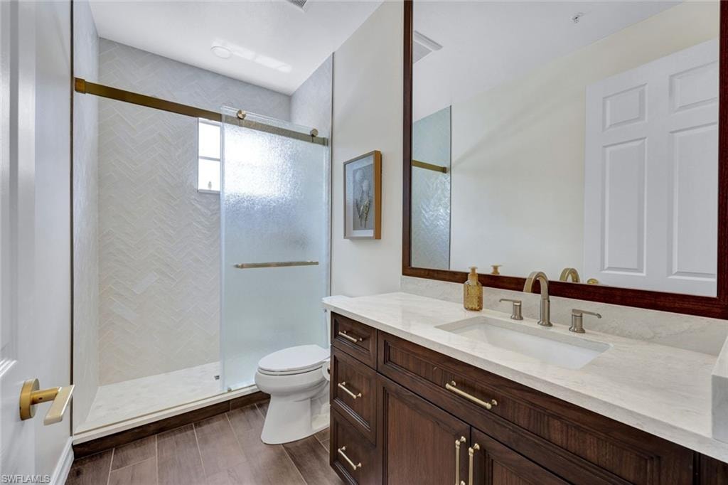 Full bath featuring a shower stall, vanity, and dark wood-style flooring