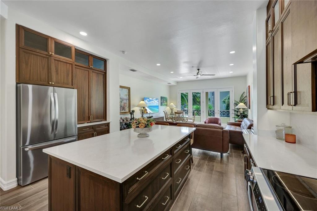 Kitchen with glass insert cabinets, appliances with stainless steel finishes, dark wood-type flooring, recessed lighting, and a kitchen island