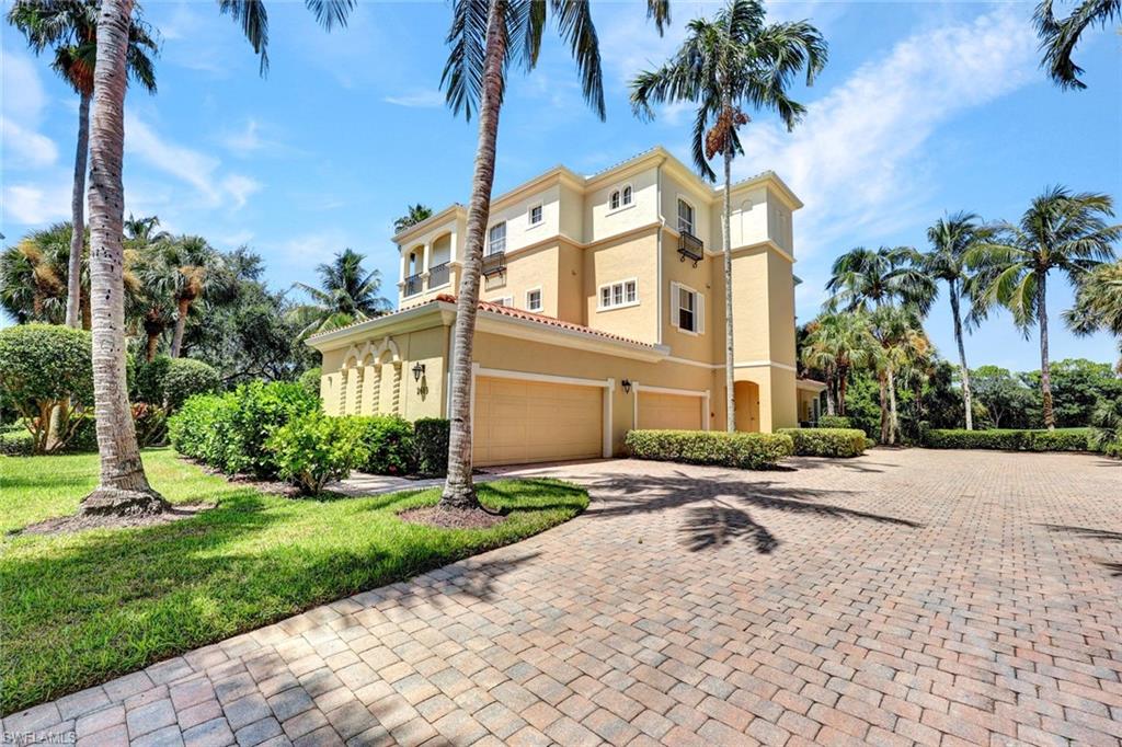 View of side of property with decorative driveway, stucco siding, an attached garage, and a yard