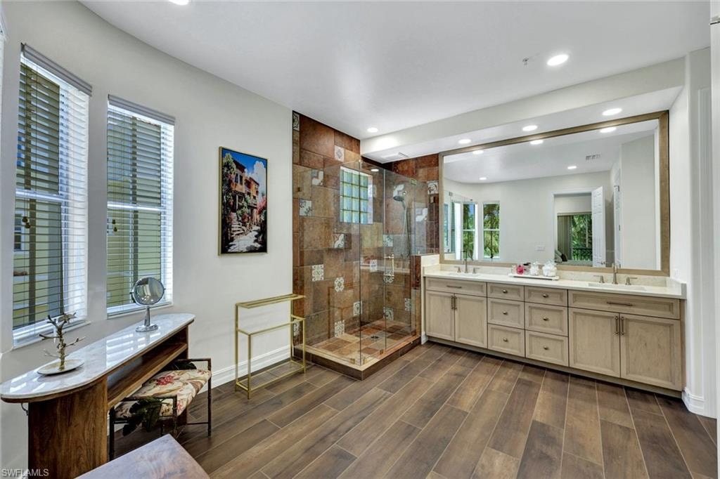 Full bathroom featuring a stall shower, double vanity, wood tiled floors, and recessed lighting