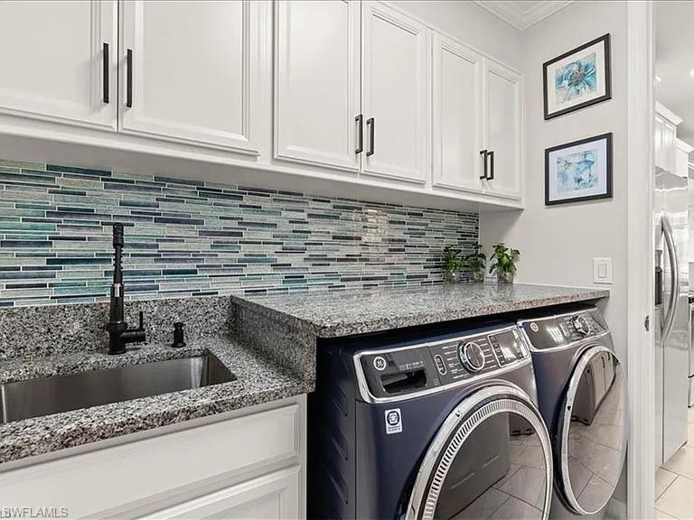 Laundry area featuring washing machine and clothes dryer, ornamental molding, and tile patterned floors