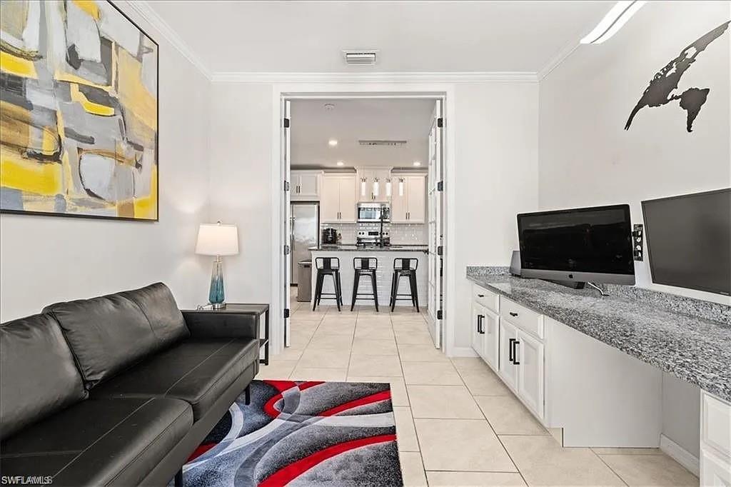 Living area with light tile patterned flooring and crown molding