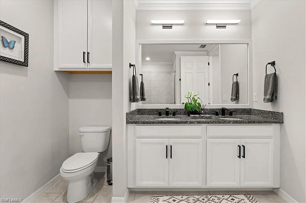 Bathroom with double vanity, crown molding, and light tile patterned floors