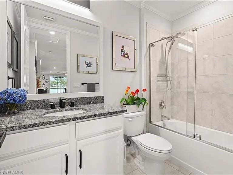 Full bath with bath / shower combo with glass door, vanity, and crown molding