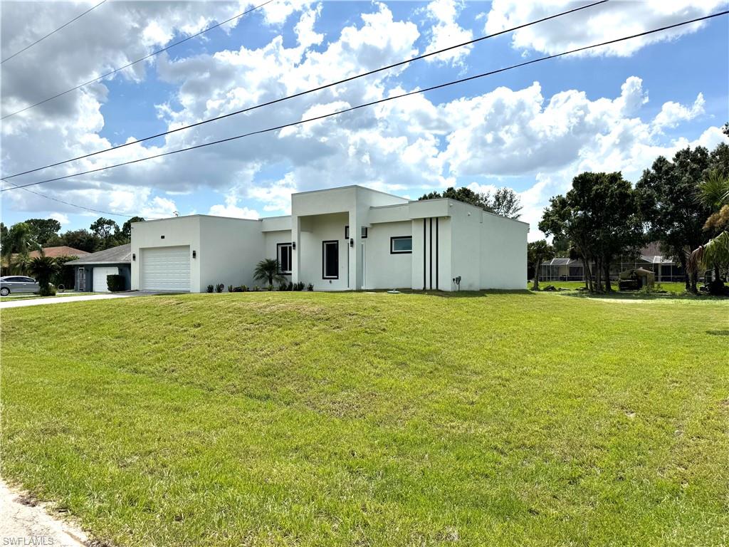 Contemporary house with decorative driveway, stucco siding, a front yard, and a garage