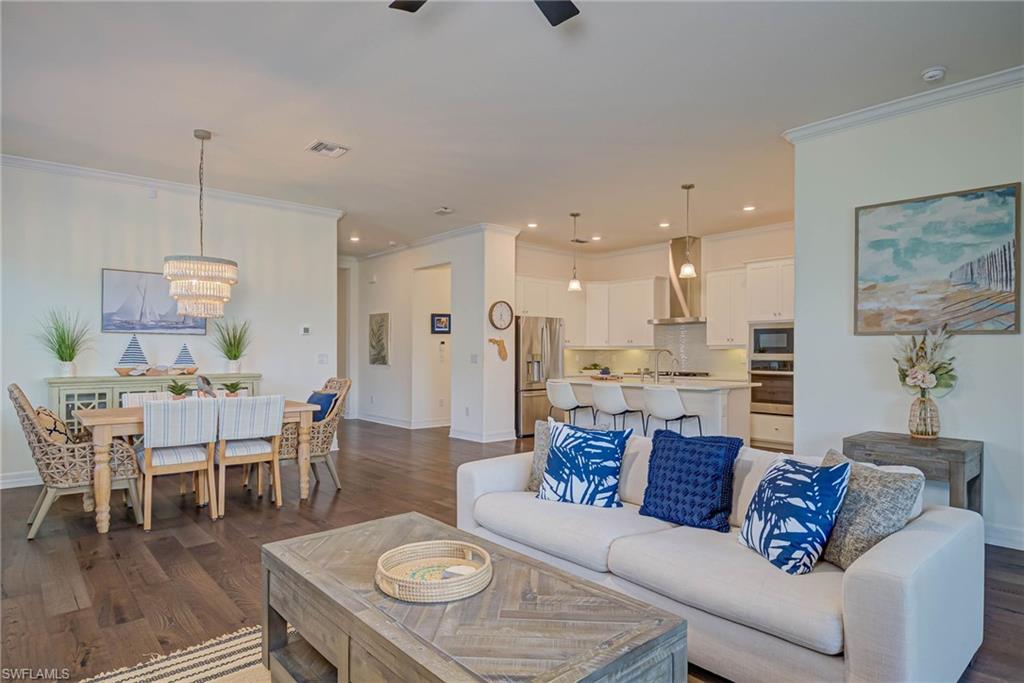Living room featuring dark wood-style flooring, ornamental molding, a chandelier, recessed lighting, and ceiling fan