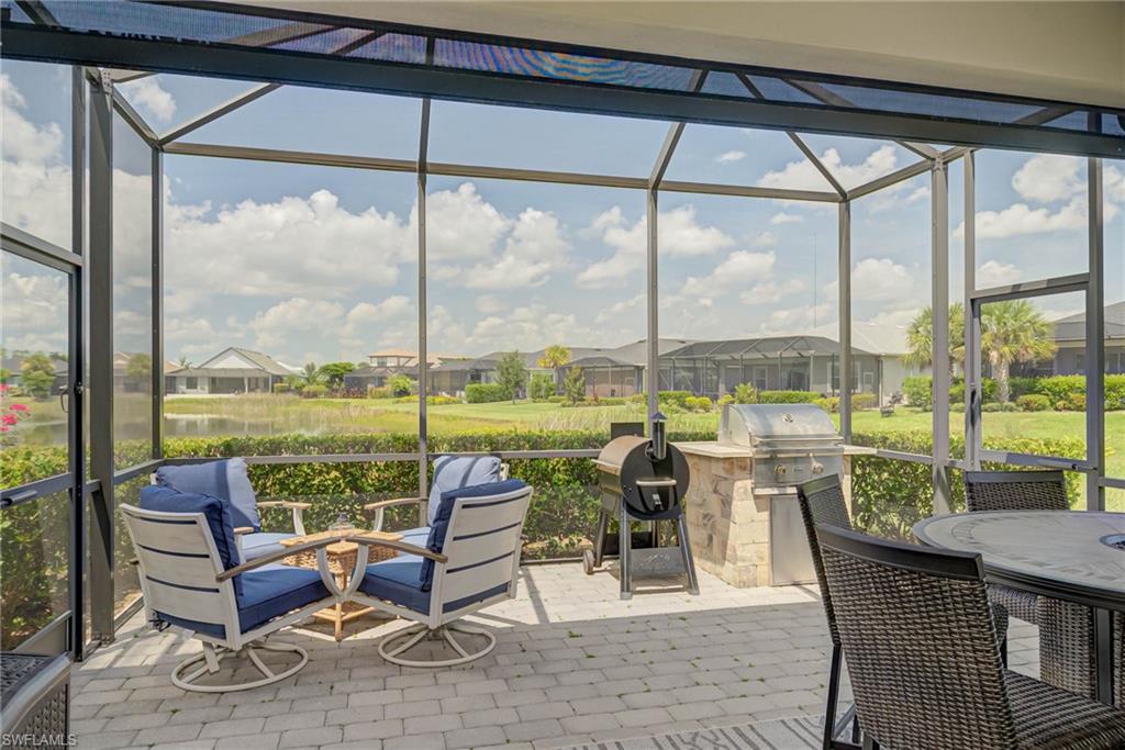 Sunroom with a residential view, healthy amount of natural light, a water view, and exterior kitchen
