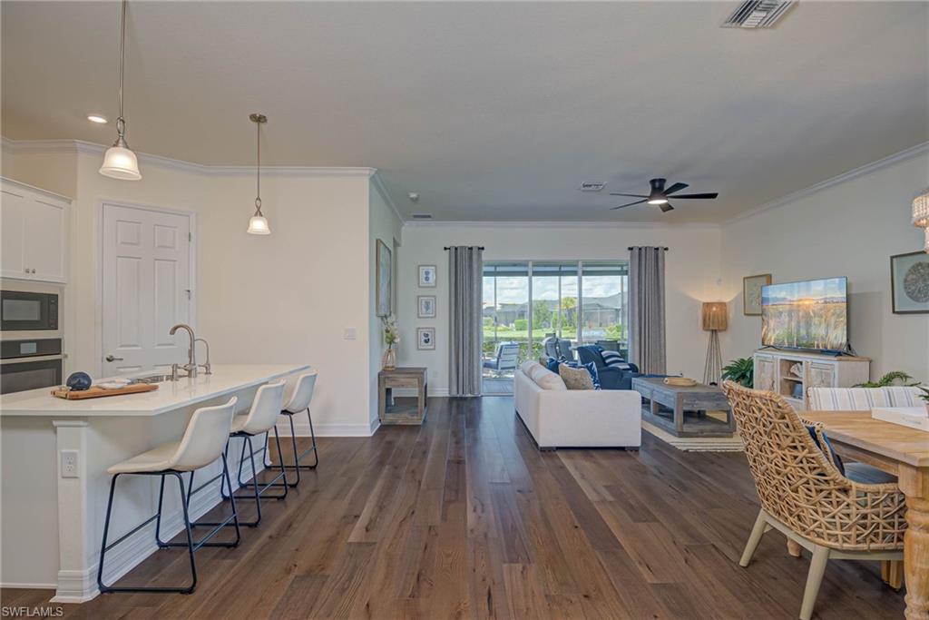 Living room featuring dark wood-style floors, ornamental molding, and ceiling fan