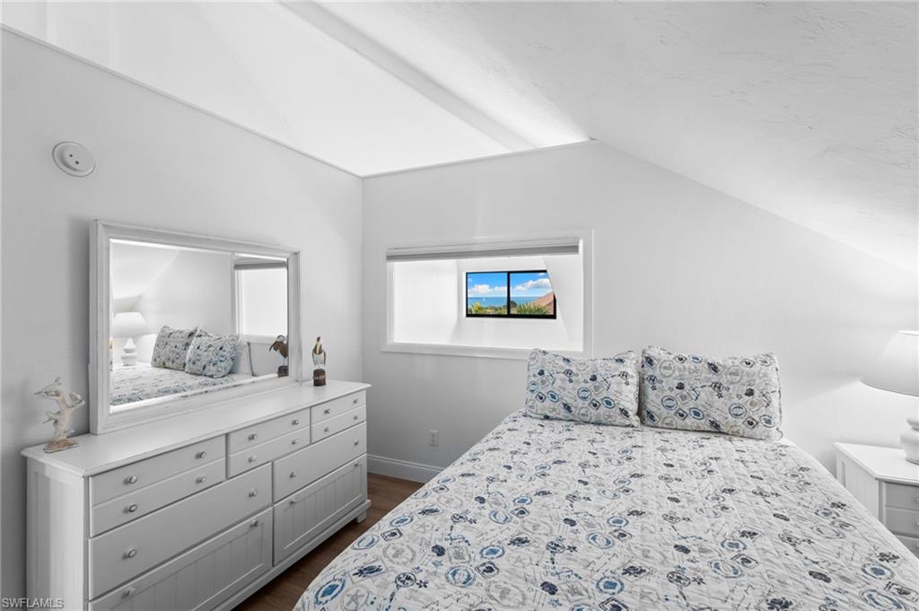 Bedroom with vaulted ceiling and dark wood-type flooring
