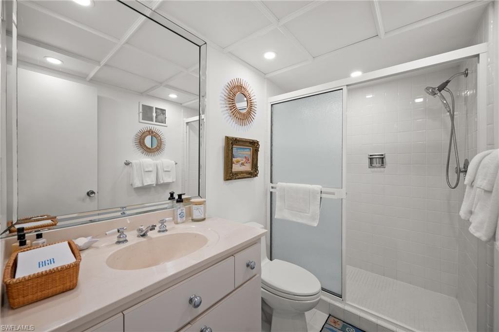Guest bedroom 1's en-suite bathroom has an oversized shower, single vanity, oversized mirror, toilet and custom lighting!