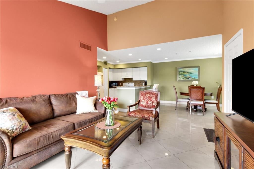 Living room with a towering ceiling, light tile patterned flooring, and recessed lighting