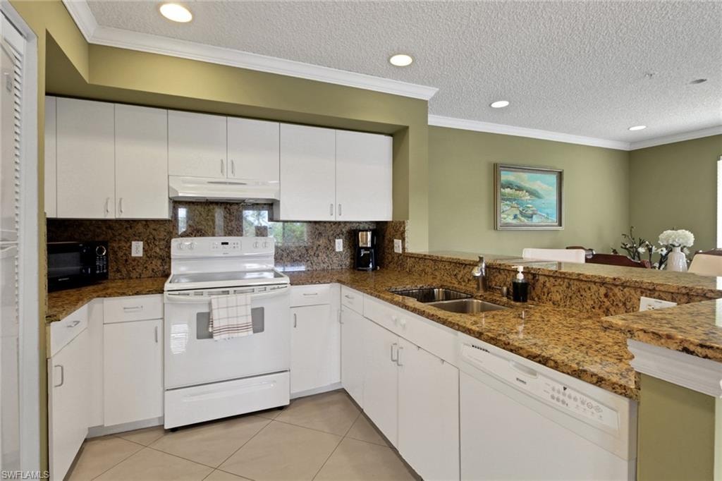 Kitchen featuring ornamental molding, white appliances, a textured ceiling, white cabinets, and light tile patterned floors