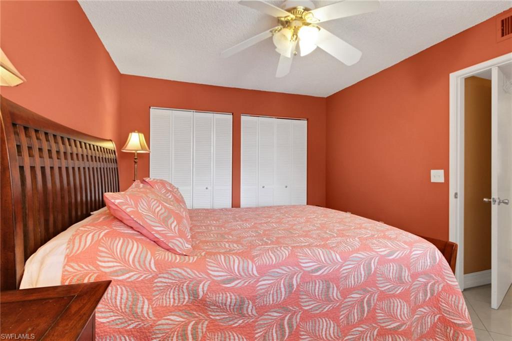 Tiled bedroom with multiple closets, a ceiling fan, and a textured ceiling