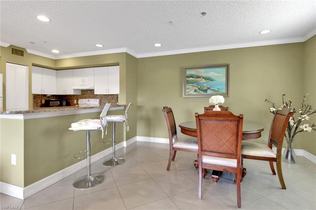 Dining space featuring ornamental molding, a textured ceiling, recessed lighting, and light tile patterned flooring