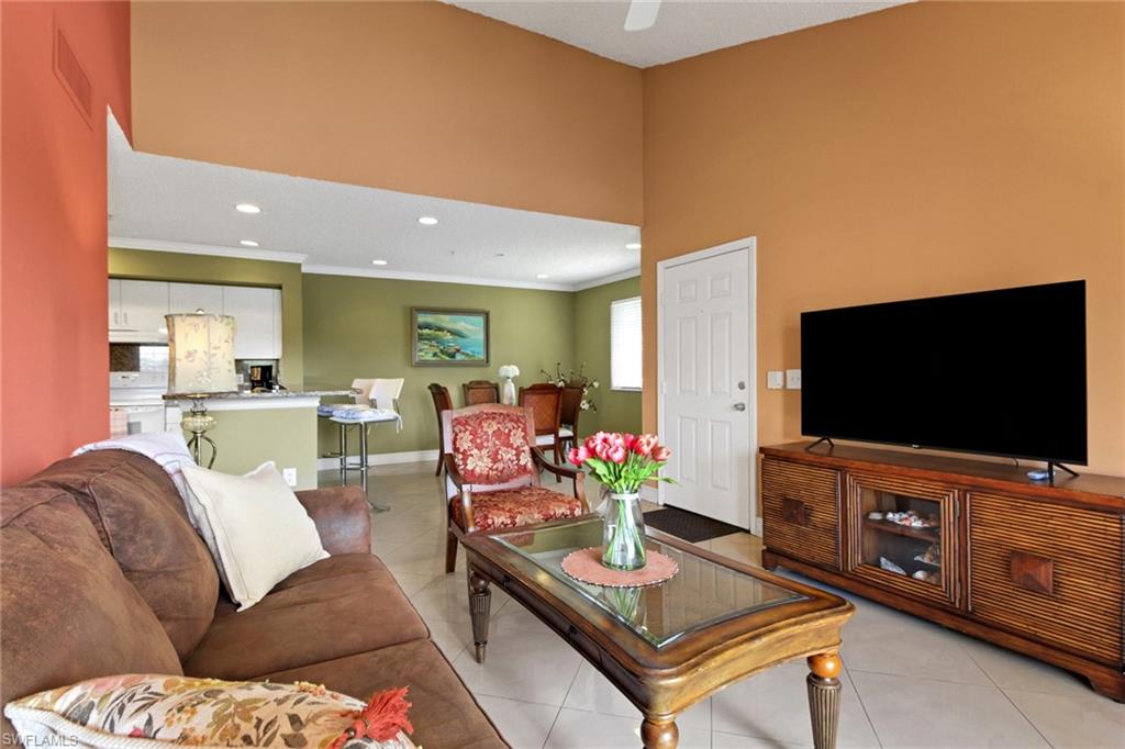 Living room with light tile patterned floors, crown molding, recessed lighting, and a towering ceiling