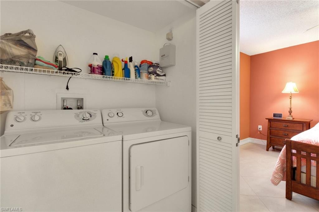 Washroom with light tile patterned floors and washer and clothes dryer
