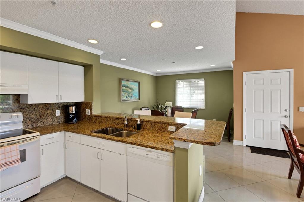 Kitchen with white appliances, a peninsula, recessed lighting, light tile patterned flooring, and a textured ceiling