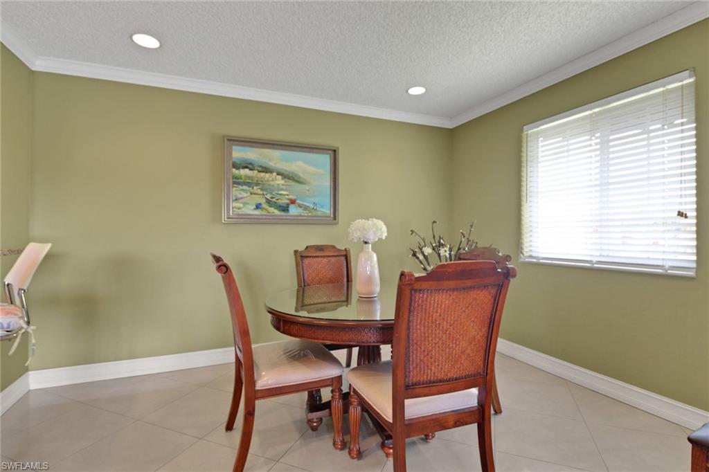 Dining space with ornamental molding, a textured ceiling, light tile patterned flooring, and recessed lighting