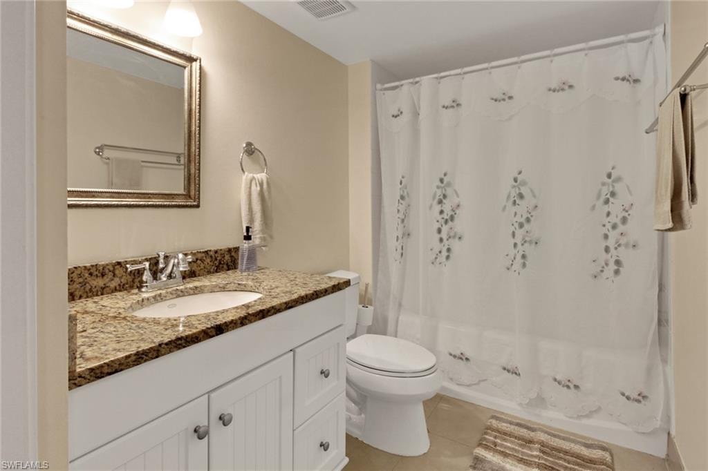 Full bath featuring vanity, light tile patterned floors, and shower / bath combo