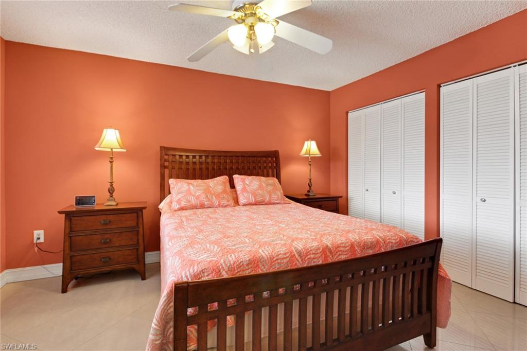 Bedroom featuring two closets, light tile patterned floors, a textured ceiling, and a ceiling fan