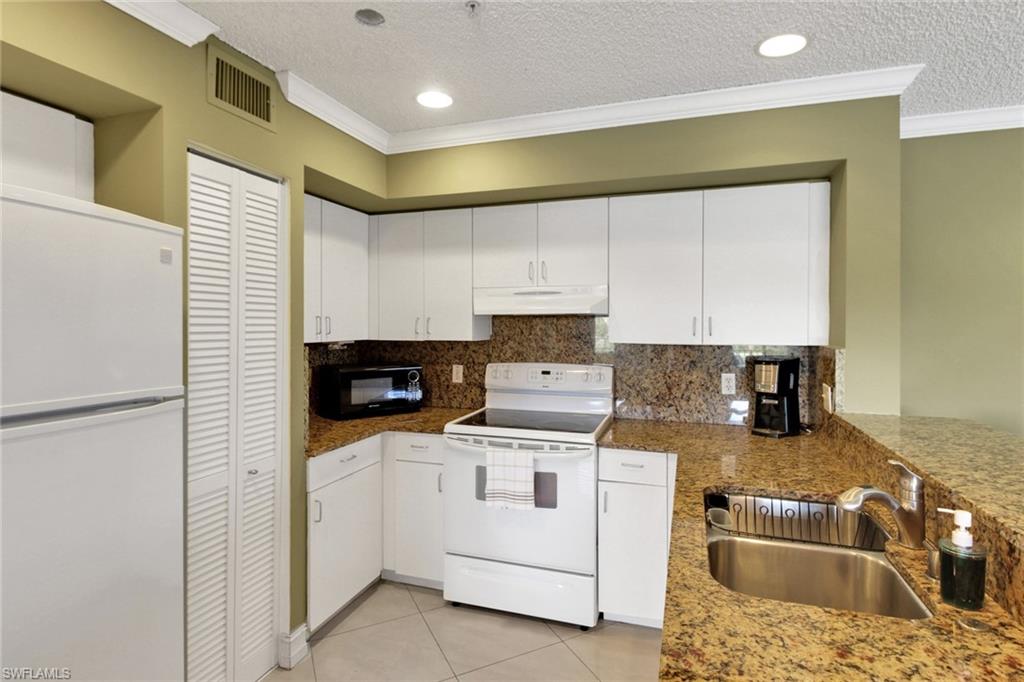 Kitchen with white appliances, crown molding, a textured ceiling, light tile patterned floors, and decorative backsplash