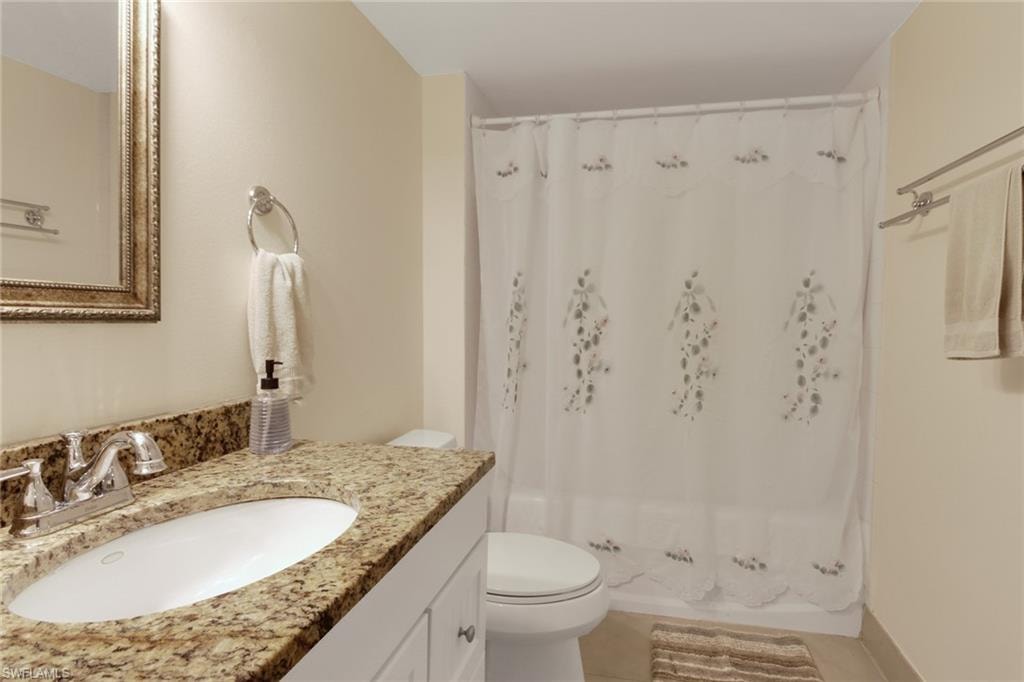 Full bath with vanity, shower / bathtub combination with curtain, and light tile patterned flooring