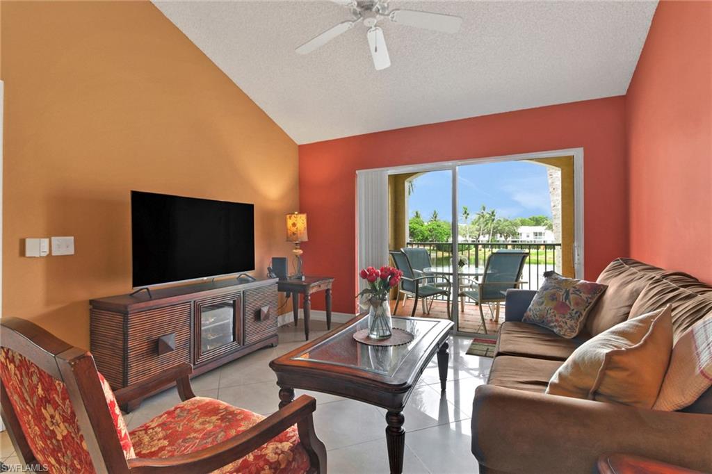 Living area featuring light tile patterned flooring, vaulted ceiling, a ceiling fan, and a textured ceiling