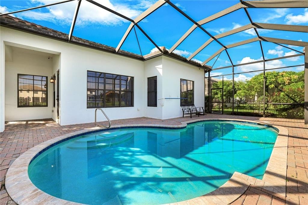 Swimming pool with a sunroom, a patio, and glass enclosure