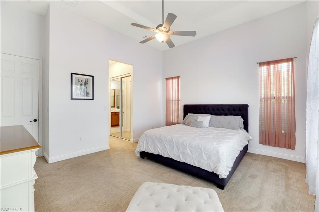 Bedroom with light carpet, a ceiling fan, a closet, and a high ceiling