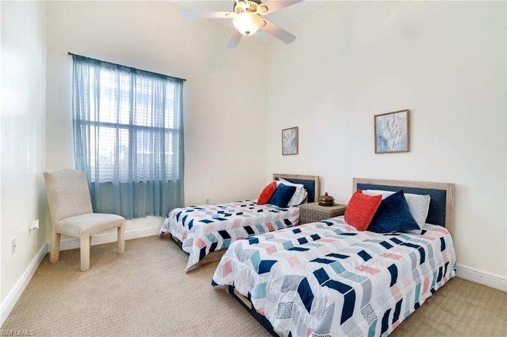 Bedroom with light carpet, ceiling fan, and a high ceiling