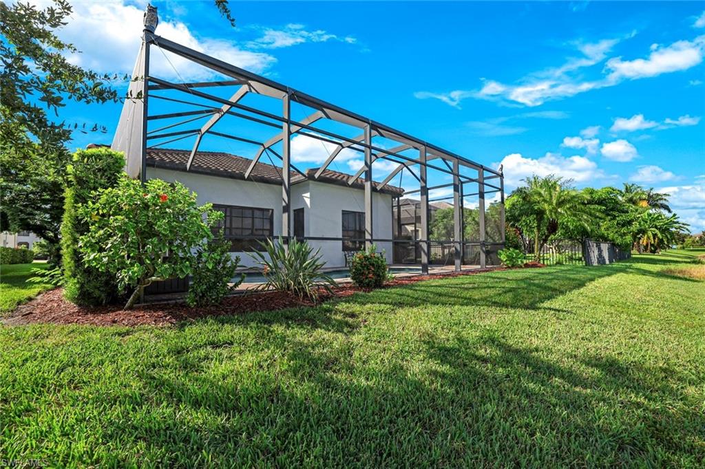 View of grassy yard featuring a sunroom and a lanai