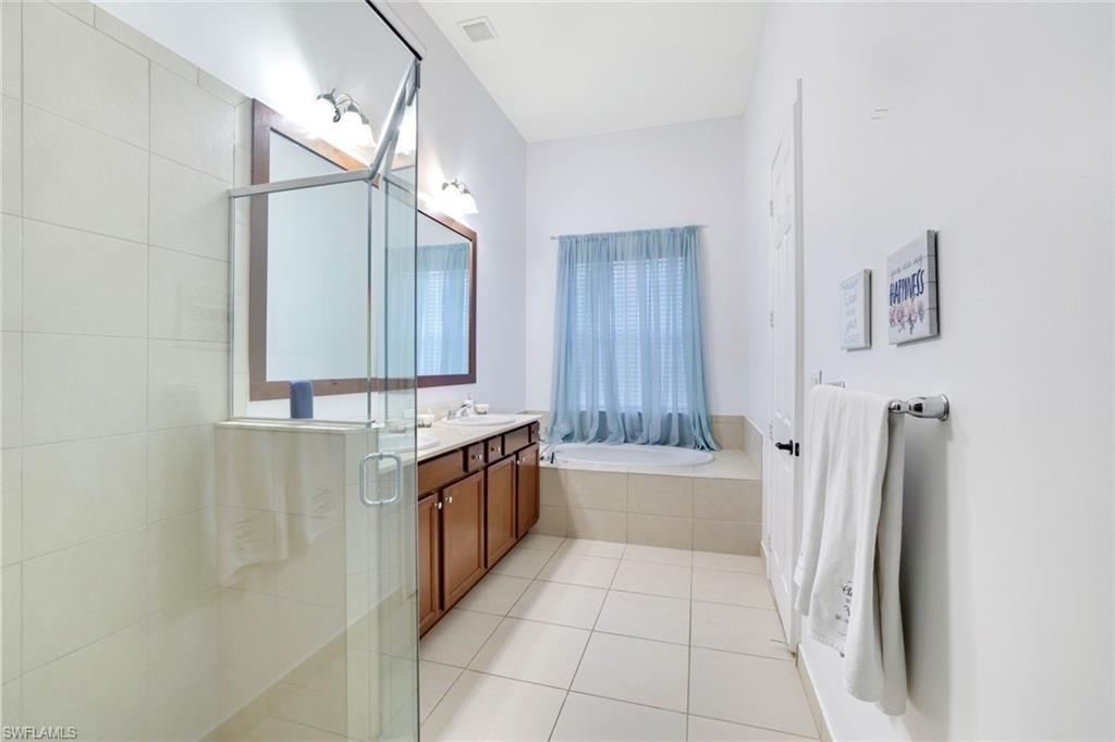 Bathroom with double vanity, light tile patterned floors, a stall shower, and a bath