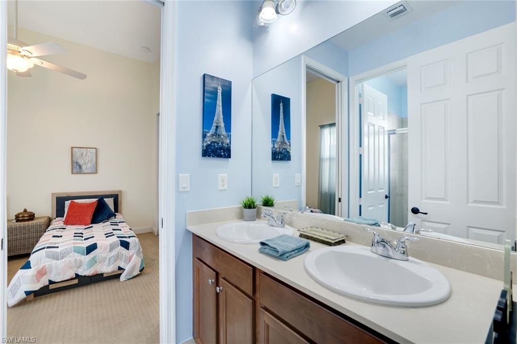Ensuite bathroom featuring double vanity, a shower stall, and ceiling fan