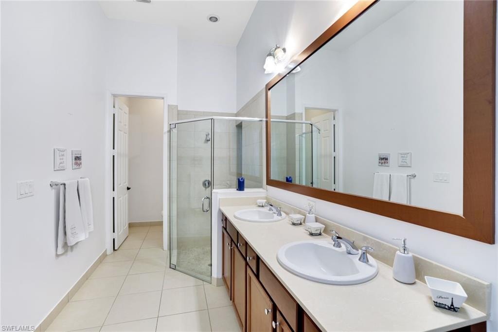 Bathroom featuring light tile patterned floors, double vanity, and a shower stall