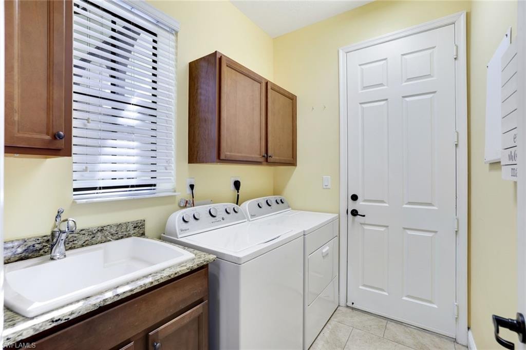 Laundry area with light tile patterned flooring, independent washer and dryer, and cabinet space