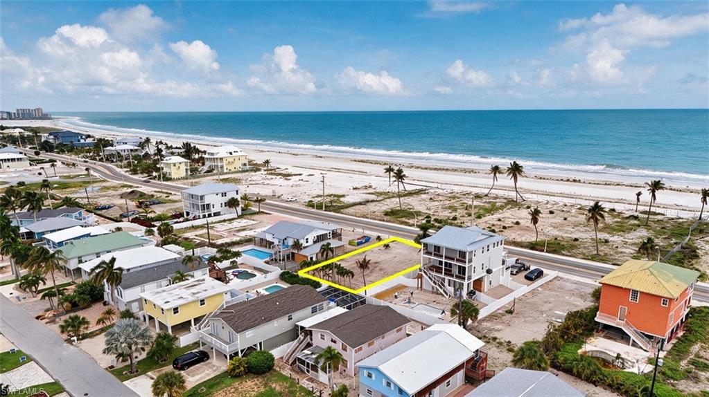 VIRTUALLY ENHANCED - Cleared lot featuring a palm tree, positioned across from a sandy beach and the ocean