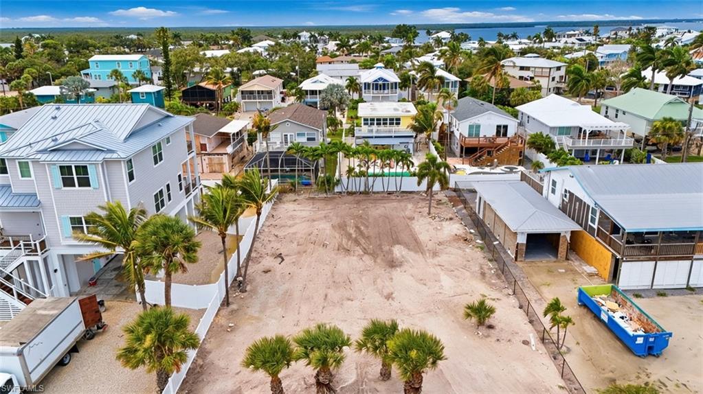 VIRTUALLY ENHANCED - Cleared building lot featuring palm trees and a white fence