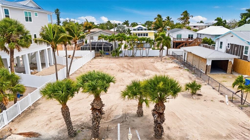 VIRTUALLY ENHANCED - Generous sandy lot featuring established palm trees and white vinyl fencing