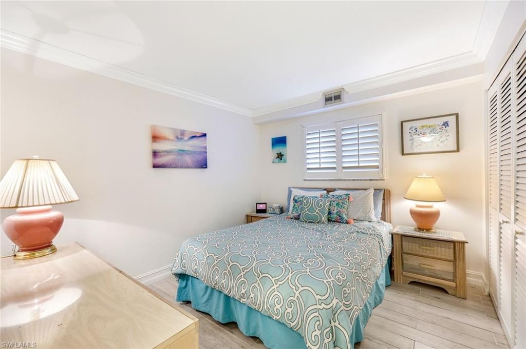 Bedroom with crown molding, wood finished floors, and a closet