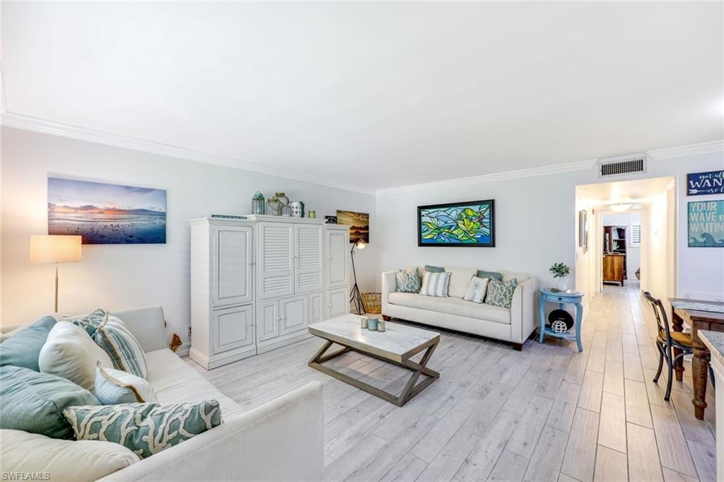 Living area with crown molding and light wood-style floors