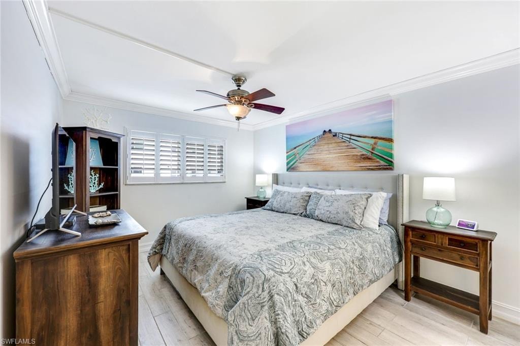 Bedroom featuring crown molding, wood finished floors, and a ceiling fan