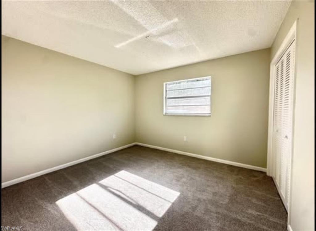 Unfurnished bedroom with a textured ceiling, carpet, a closet, and ceiling fan