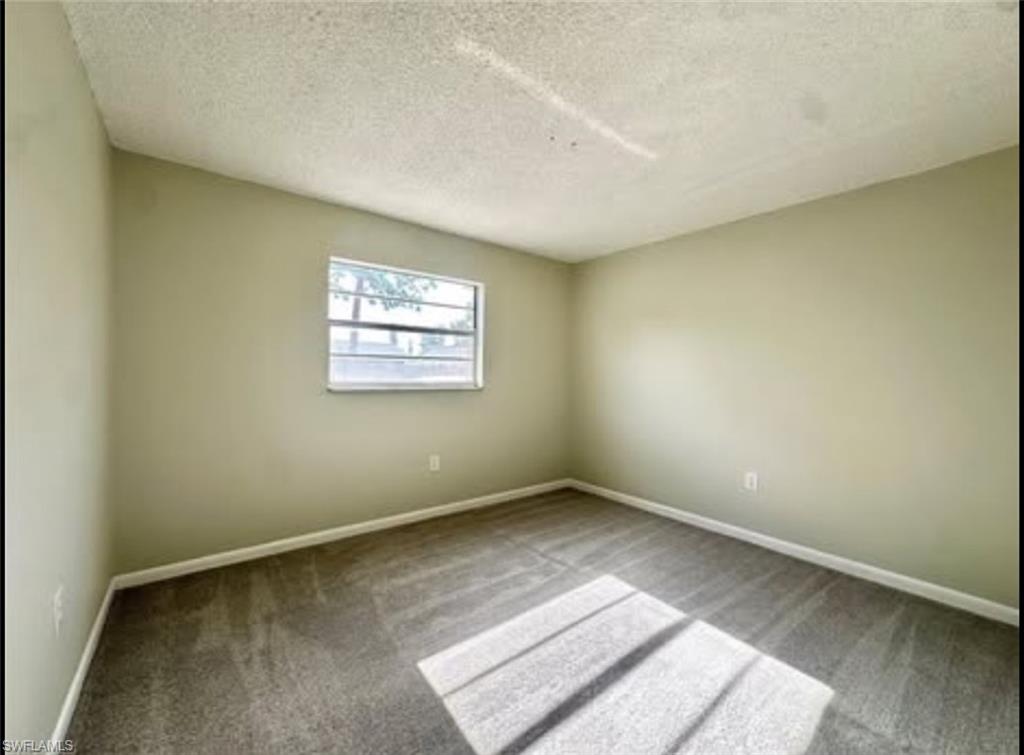Spare room with a textured ceiling and carpet