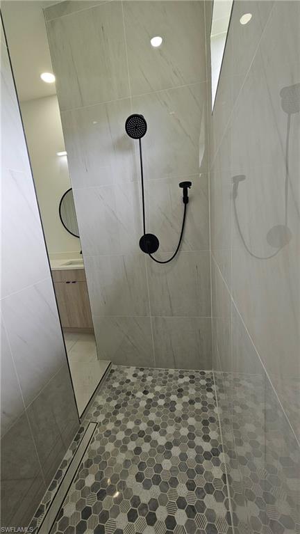 Full bath featuring tiled shower and recessed lighting