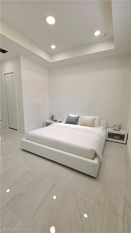 Bedroom featuring recessed lighting, a tray ceiling, and light tile patterned floors