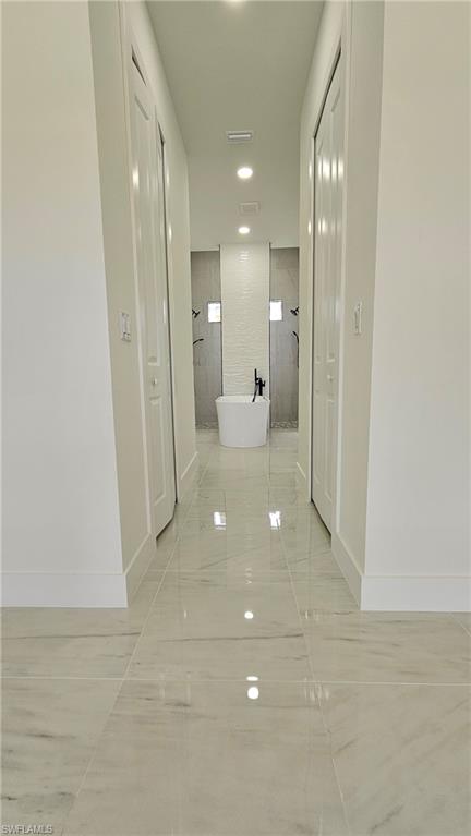 Hallway with light marble finish flooring and recessed lighting